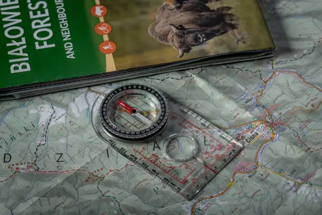 Kompas i mapa turystyczna leżą na stole.