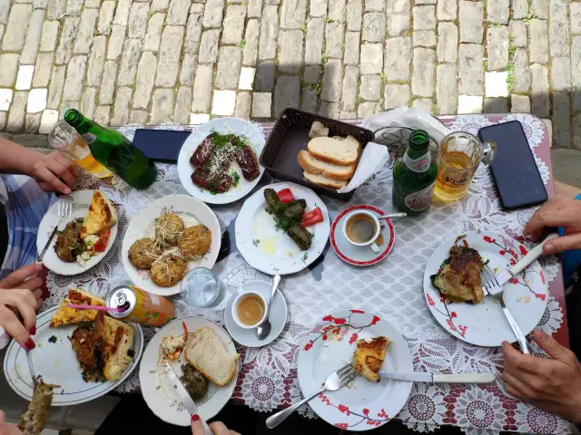 Stół zastawiony pysznym jedzeniem, typowym dla Albanii. Widać dania mięsne, gołąbki, pieczywo, kawę i piwo.