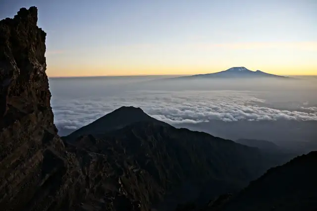 Widok z góry na morze chmur, z górującym w oddali majestatycznym Mount Meru.