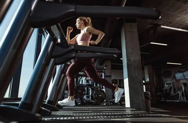 Mujer corriendo en una cinta de correr en un gimnasio moderno.