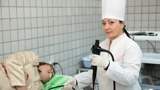Lekarka przygotowuje się do gastroskopii. Pacjent leży na stole. Czy przed gastroskopią można brać leki? Zapytaj lekarza.