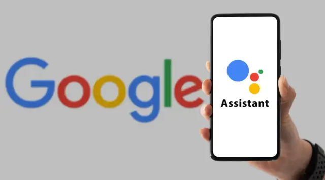Dłoń trzyma smartfon z logo Asystenta Google na ekranie, w tle logo Google.