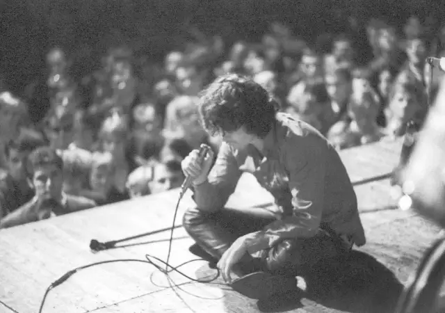 Jim Morrison z The Doors na scenie, wpatrzony w tłum. Jego "Paris Blues" rozbrzmiewa w sercach fanów.
