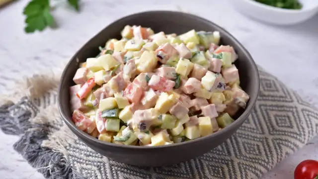 Sałatka z szynką i żółtym serem i jajkiem, z dodatkiem ogórka i pomidora, polana kremowym sosem.