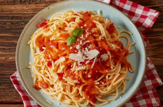 Pyszne spaghetti z sosem pomidorowym, parmezanem i listkiem bazylii. Idealne co do spaghetti na szybki obiad.