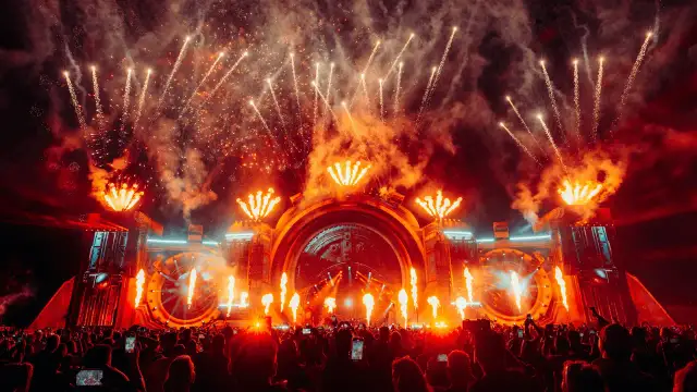 Spektakularny pokaz fajerwerków i płomieni na scenie podczas festiwalu Sunrise Festival 2026. Tłum ludzi z telefonami wzniesionymi ku górze.