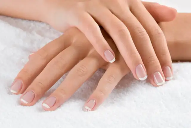 Dłonie z klasycznym french manicure. Delikatny róż i biel sprawiają, że palce wyglądają na dłuższe i smuklejsze. Jaki kolor paznokci wyszczupla palce? Ten subtelny french manicure!
