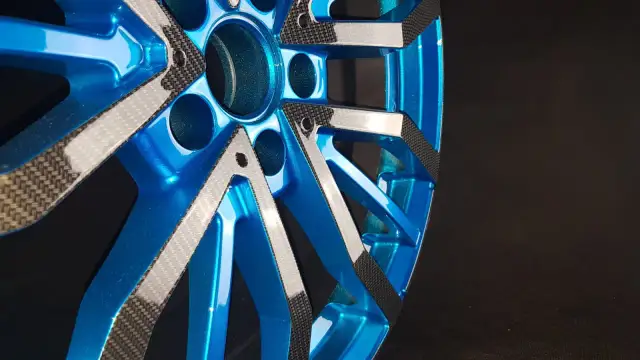 Błyszczące niebieskie felgi z elementami imitującymi włókno węglowe.