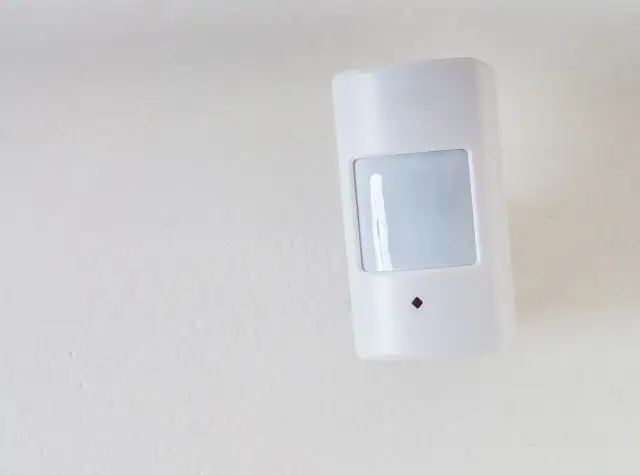 Biały czujnik ruchu na ścianie. Zastanawiasz się, gdzie zamontować czujnik gazu? Ten model jest dobrym przykładem, jak dyskretnie umieścić urządzenie.
