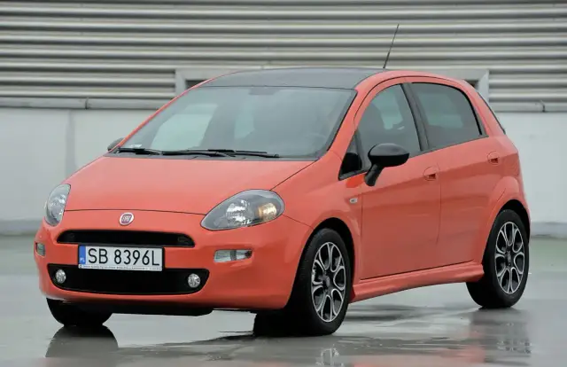 Pomarańczowy Fiat Punto na mokrej nawierzchni. Zwróć uwagę na jego kompaktowe fiat punto wymiary, idealne do miasta.