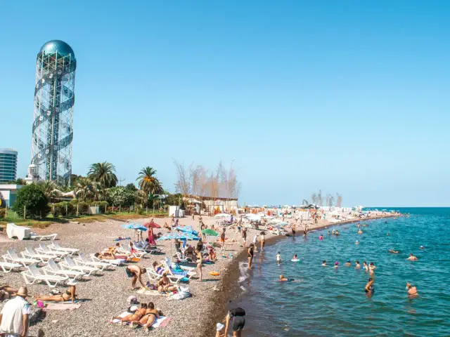 Tłum ludzi na plaży w Batumi, Gruzja. W tle charakterystyczna wieża. Odpowiedź na pytanie: czy w Gruzji jest bezpiecznie? Tak, plaże są pełne turystów.