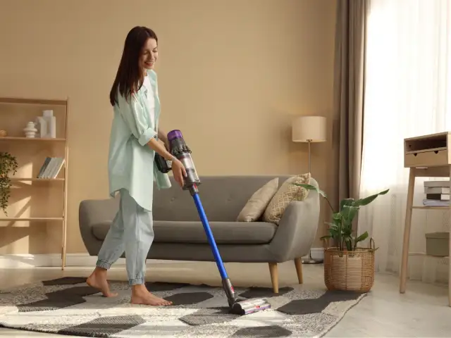 Kobieta sprząta salon odkurzaczem Dyson.