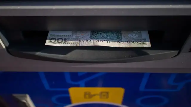 Jednorazowa wpłata gotówki do bankomatu. Banknot 100 zł wchodzi do szczeliny.