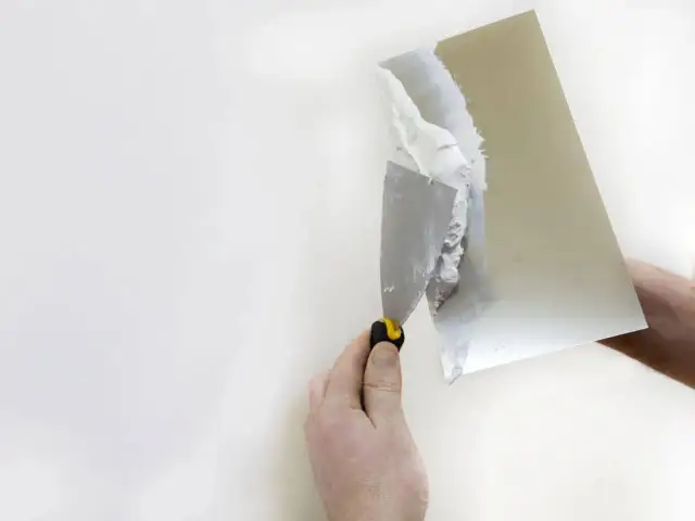 Nakładanie gładzi na karton gips. Ręka trzymająca kielnię z masą szpachlową, przygotowuje ścianę do malowania.