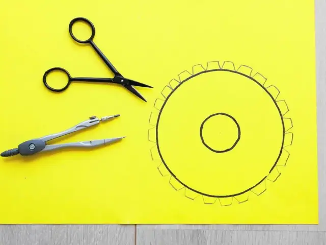 Narzędzia do tworzenia: cyrkiel, nożyczki i narysowany okrąg z ząbkami. Idealne do nauki, jak zrobić abażur walec.