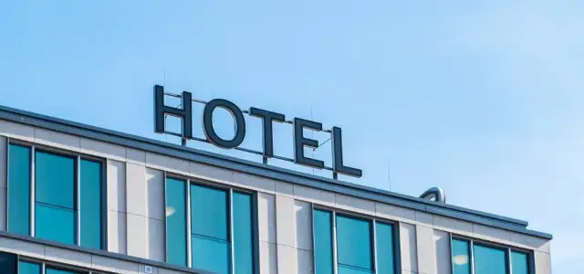 Znak "HOTEL" na dachu nowoczesnego budynku z niebieskimi oknami. Marzenie o tym, jak założyć hotel, zaczyna się od takiego widoku.