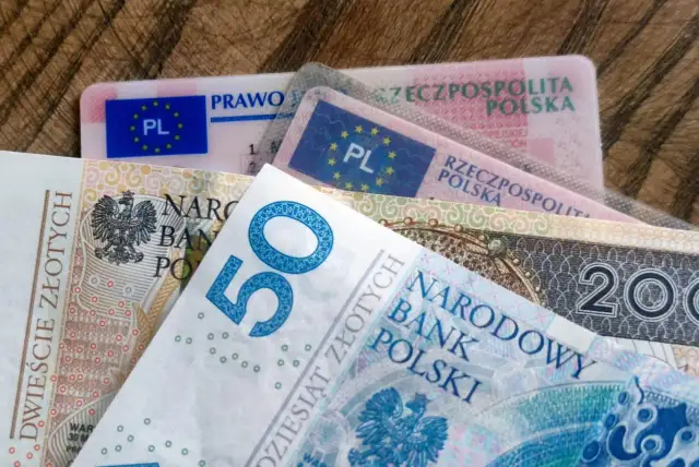 Polskie prawo jazdy i banknoty 50 zł, 200 zł na drewnianym tle.