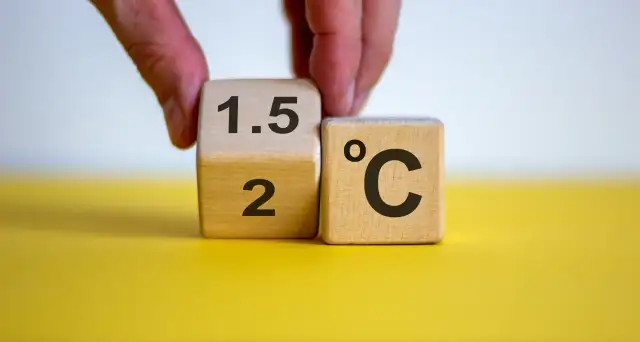Dłoń obraca kostkę z "2" na "1.5", symbolizując cel paryskiego porozumienia klimatycznego.