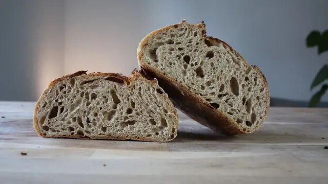 Chleb pszenno żytni na zakwasie, przekrojony na pół, prezentuje apetyczny, porowaty miąższ i chrupiącą skórkę.
