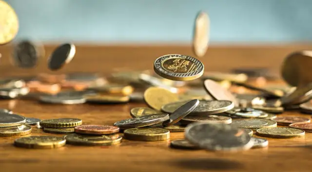 Monety spadają na drewniany blat. Zastanawiasz się, jak wyczyścić monety domowym sposobem? Oto kilka wskazówek.