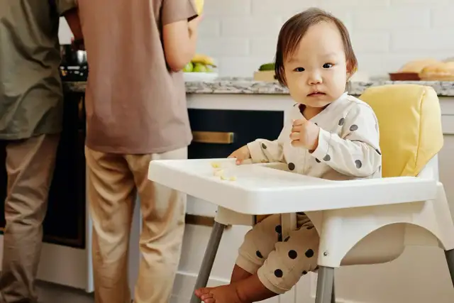 Małe dziecko w krzesełku do karmienia od kiedy zaczyna jeść stałe pokarmy.