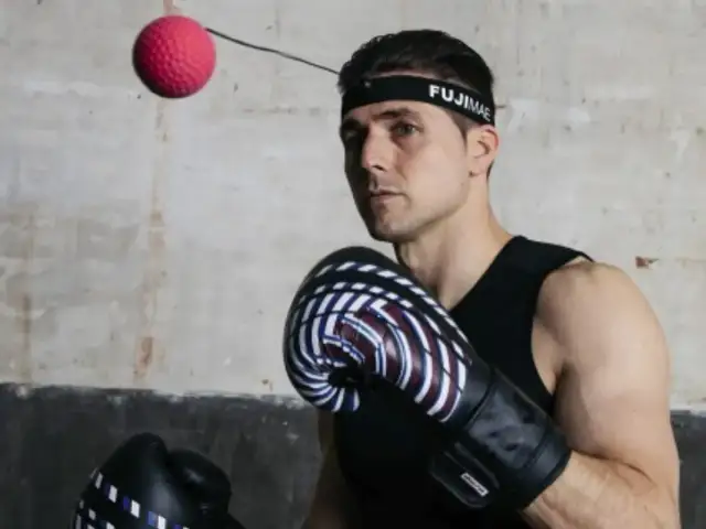 Bokser w rękawicach i opasce FUJIMAE, japoński producent sprzętu sportowego, ćwiczy z piłką refleksyjną.