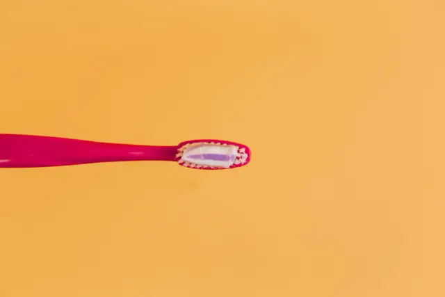 Różowa szczoteczka z pastą do zębów, zawierającą fluorek sodu, gotowa do walki z próchnicą. Fluor to klucz do zdrowych zębów.