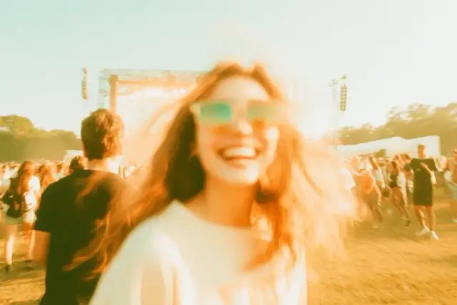 Szczęśliwa dziewczyna w okularach na festiwalu, gdzie grają wszystkie baciary piosenki. Tłum ludzi bawi się przy muzyce.