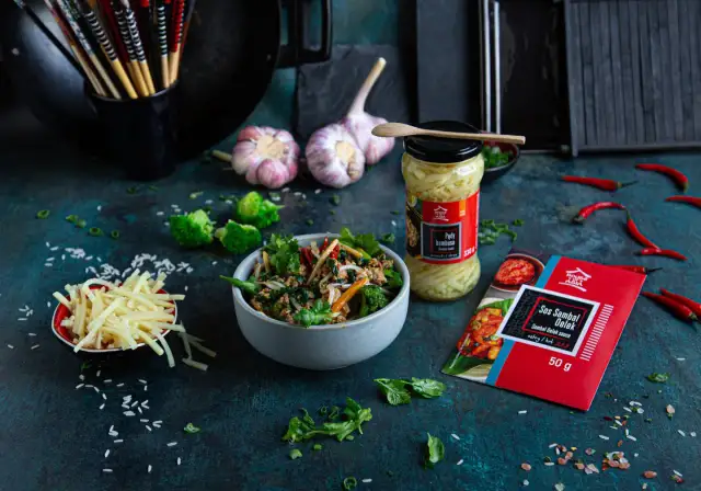 Miseczka z daniem w sosie sojowym, obok słoik pędów bambusa, czosnek, chili i ryż.