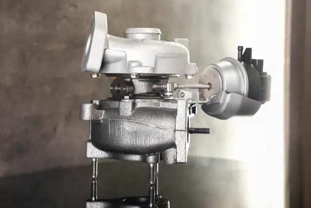 Turbocharger z siłownikiem podciśnienia na szarym tle.