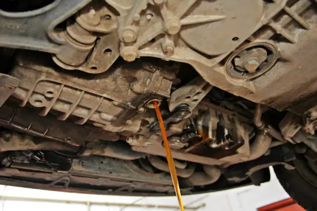 Płynny strumień oleju spływa z automatycznej skrzyni biegów podczas jej wymiany.