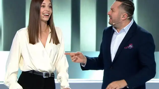 Kobieta i mężczyzna rozmawiają na scenie, mężczyzna wskazuje palcem.