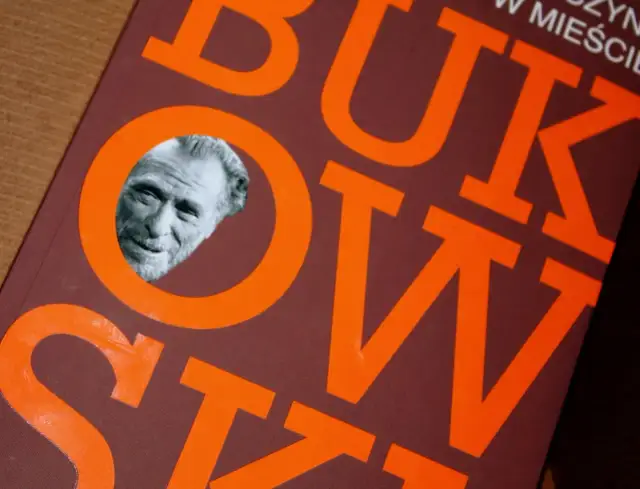 Portret Charlesa Bukowskiego w okrągłym wycięciu na okładce książki z pomarańczowymi literami.