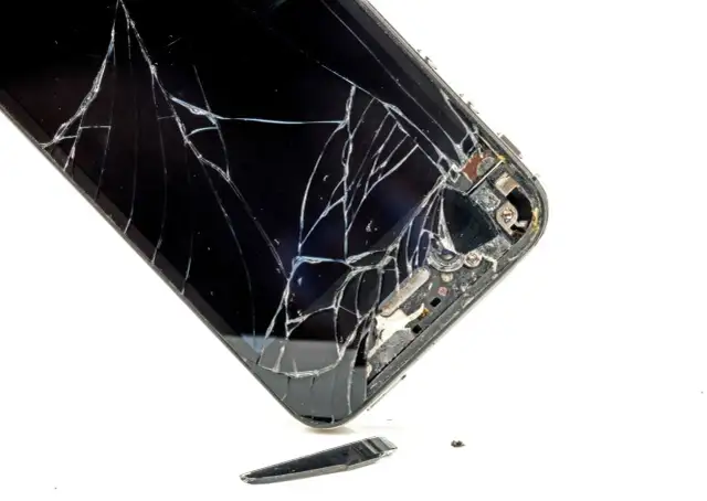 Rozbite szkło telefonu. Widać pęknięcia i fragmenty, które odpadły. To pokazuje, czym się różni szkło hartowane od hybrydowego w praktyce.