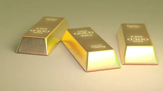 Trzy sztabki złota, każdy o wadze 1000g, z napisem "FINE GOLD 999.9". Ten szlachetny metal lśni w świetle.