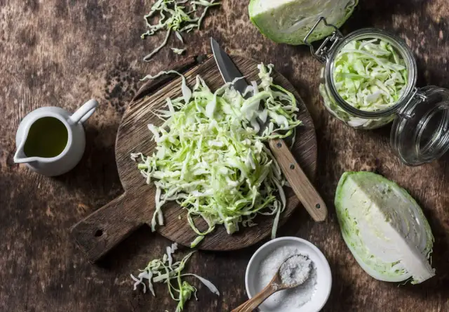 Składniki na dietę kapuścianą: poszatkowana kapusta, sól, oliwa i nóż na desce. Przepis na 7 dni.