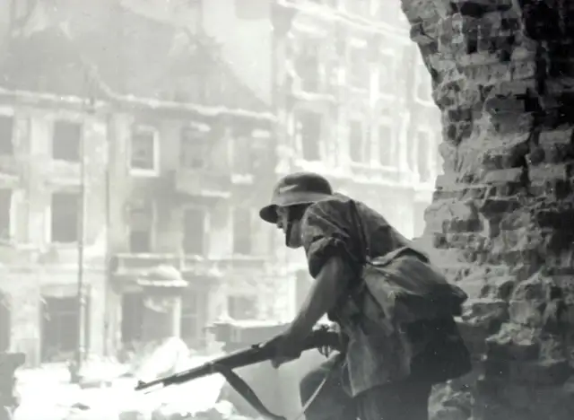 Żołnierz z karabinem w ruinach miasta. Czy powstanie warszawskie miało sens? Pytanie to wciąż budzi emocje.