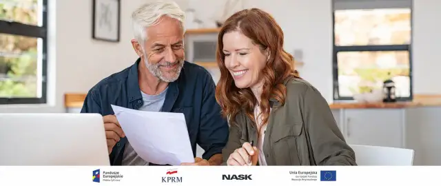 Uśmiechnięta para przegląda dokumenty przy laptopie.