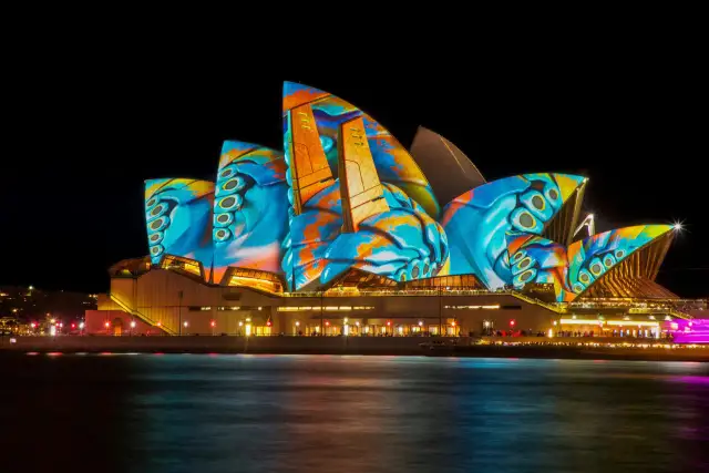Sydney Opera House nocą, oświetlona kolorowymi projekcjami.