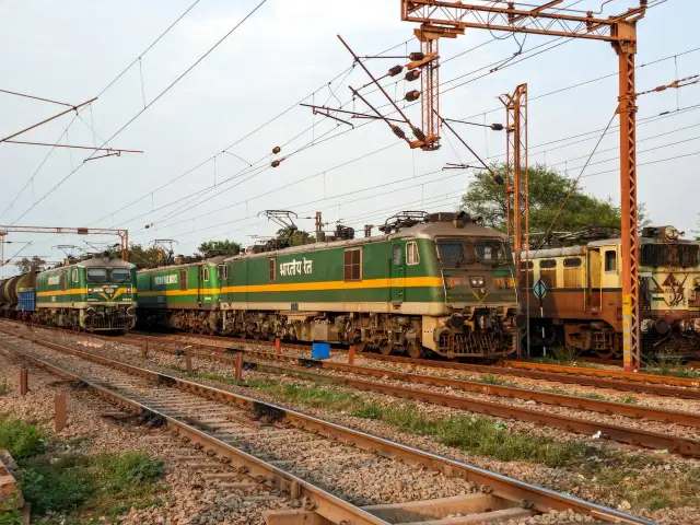 Zielone lokomotywy elektryczne stojące na torach kolejowych pod siecią trakcyjną.