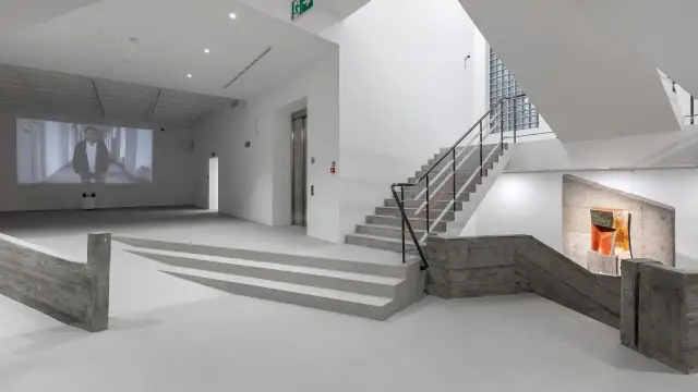 Wnętrze muzeum sztuki współczesnej Kraków: projekcja wideo, betonowe schody i rzeźba.