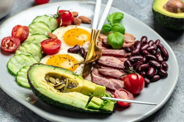 Talerz z jajkami sadzonymi, boczkiem, awokado, fasolą i warzywami. Czy dieta keto jest zdrowa?