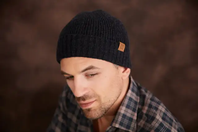 Mężczyzna w czarnej czapce z naszywką. Dowiedz się, jak zmierzyć rozmiar czapki, aby idealnie pasowała.