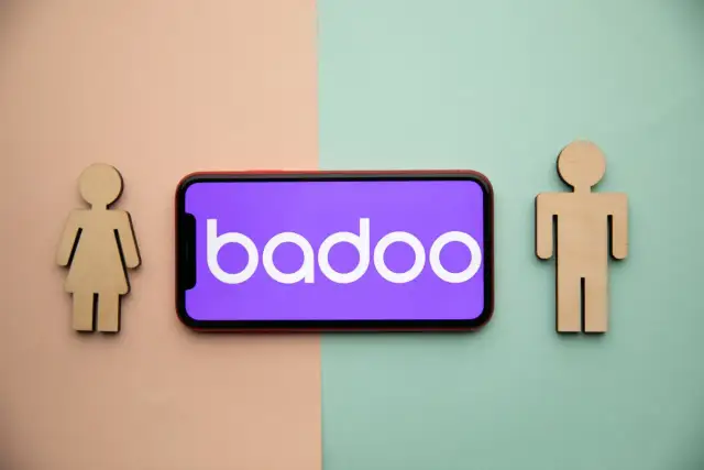 Drewniane figurki kobiety i mężczyzny po bokach telefonu z logo Badoo. Czy to portal randkowy?