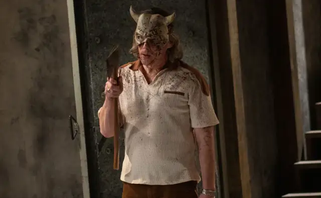 Mężczyzna w masce z rogami, ubrany w poplamioną koszulkę, trzyma siekierę. To złowieszczy czarny telefon obsada.