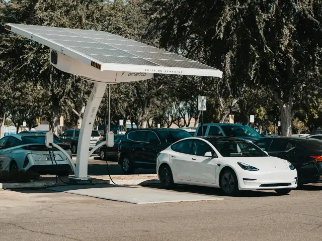 Biała Tesla z USA ładuje się pod panelem słonecznym.
