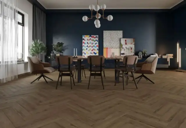 Drewniana podłoga w jodełkę, ciemne ściany, stół z krzesłami i fotele.