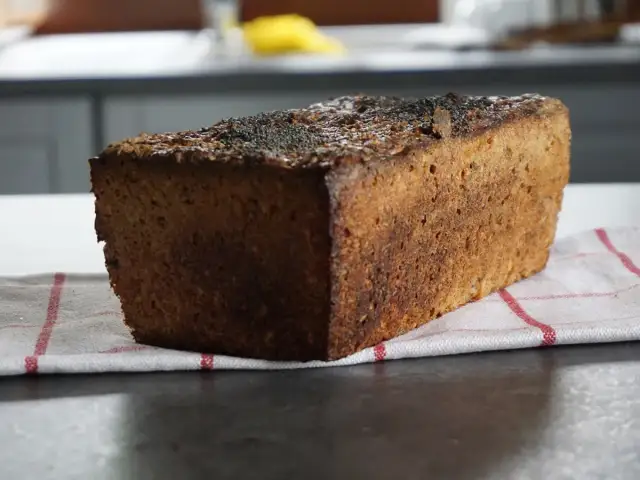 Bochenek ciemnego chleba żytniego z makiem na kuchennym blacie.