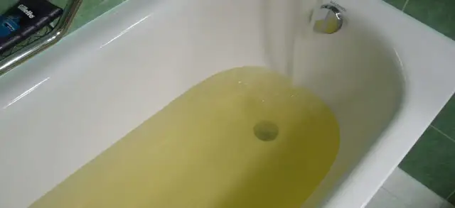 Wanna z żółtą wodą, z kranu leje się woda.
