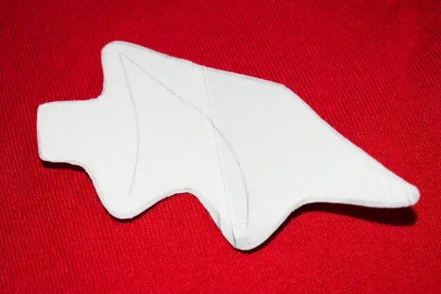 Biały, wycięty kształt na czerwonym tle, przypominający szablon do wykonania ogona diabła.